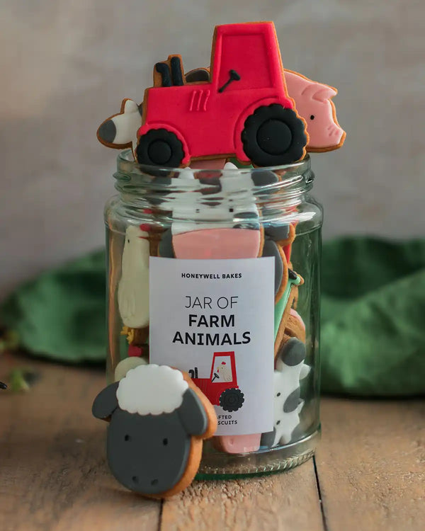 Honeywell Bakes Personalised Jar of Farm Animal Biscuits - Jar of farm animal cookies with a red tractor cookie on top, surrounded by greenery.
