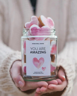 Honeywell Bakes Personalised Jar of Heart Biscuits - Jar of pink and white cookies with a 'You are Amazing' label held by a person.