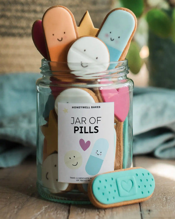 Personalised jars of colourful biscuit pills decorated with smiley faces, hearts, plasters and stars, ideal for fun and thoughtful gifting.