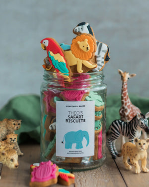 Honeywell Bakes Personalised Jar of Safari Biscuits - Jar of 'Theo's Safari Biscuits' with animal-themed cookies and small toy animals on a wooden surface.