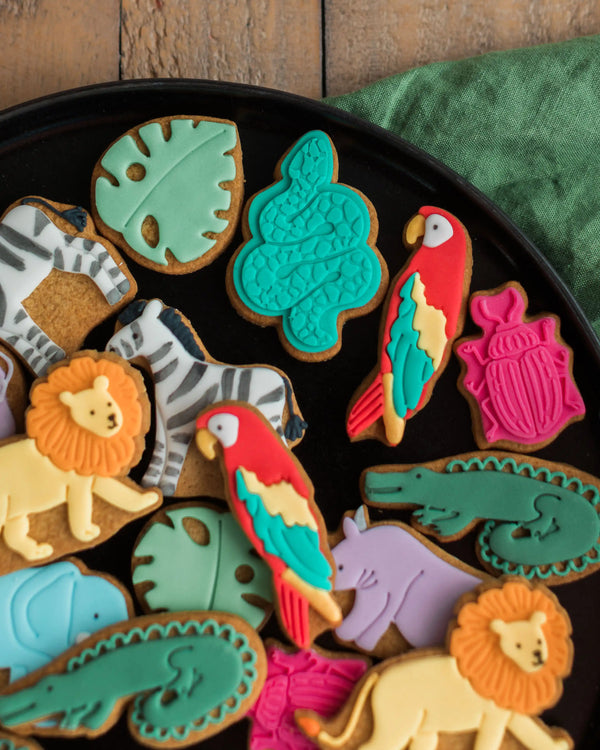 Honeywell Bakes Personalised Jar of Safari Biscuits - Assorted animal-shaped cookies on a black plate with a wooden background