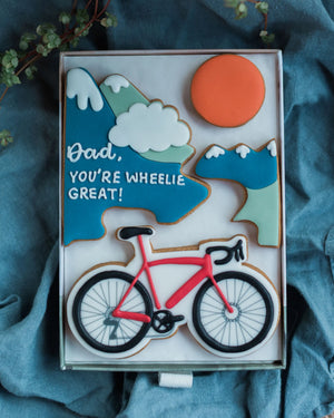 Honeywell Bakes Personalised Medium Bicycle Biscuit Gift - Bike-themed biscuit set with 'Dad, you're wheelie great!' message on a blue fabric background