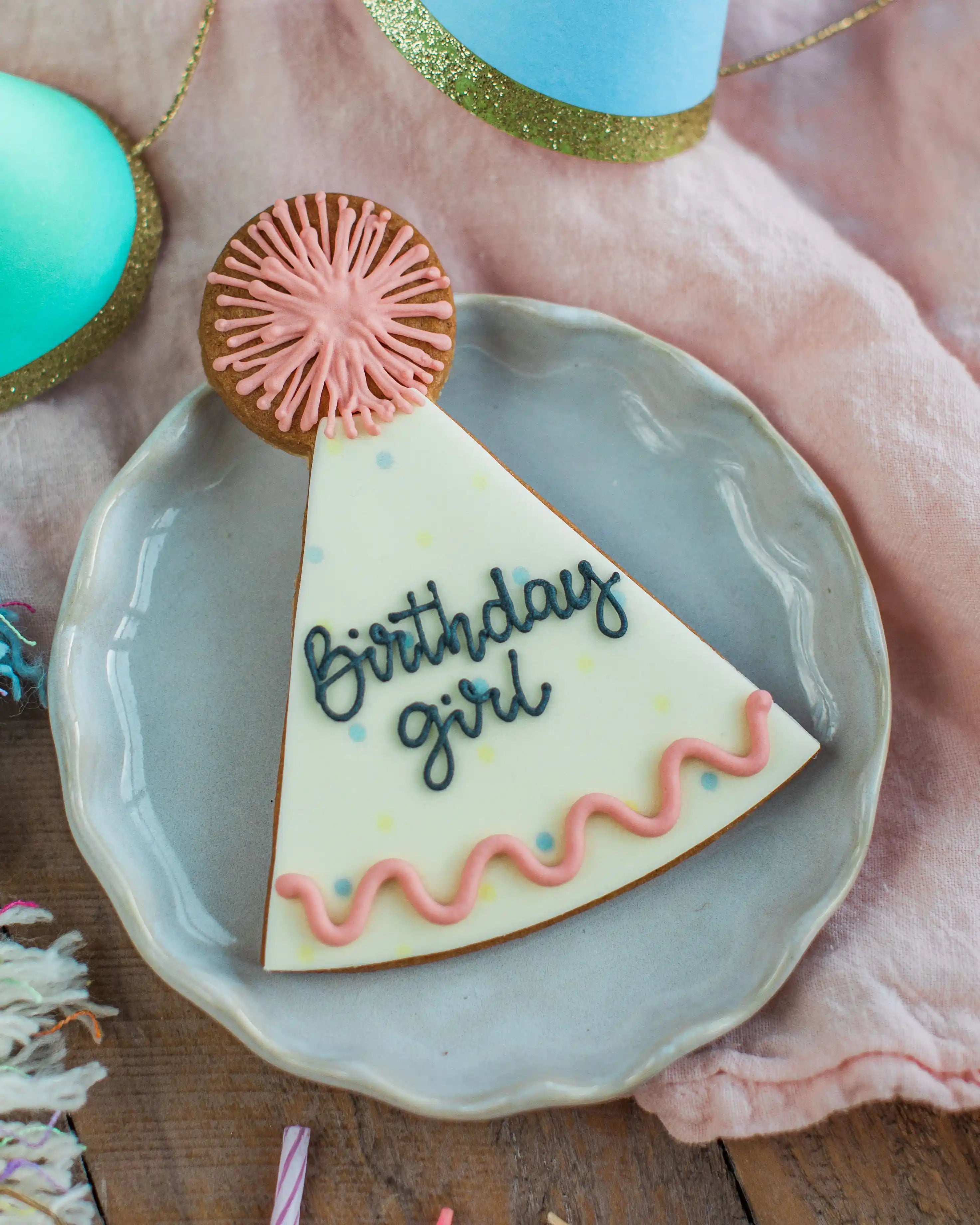 Honeywell Bakes Personalised Party Hat Biscuit - Decorative cookie shaped like a birthday hat with 'Birthday girl' text on a plate.