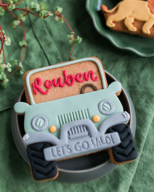 Honeywell Bakes Personalised Safari Car Biscuit - Cookie decoration shaped like a truck with 'Reuben' and 'Let's Go Wild!' text on a green background.