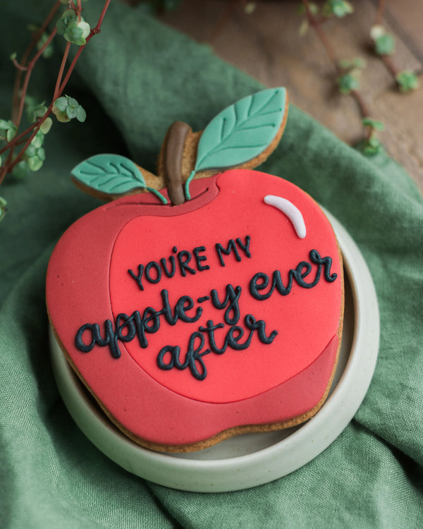 Honeywell Bakes Personalised Thank You Teacher Apple Biscuit - Red apple-shaped cookie with 'You're my apple-y ever after' text on a green cloth background