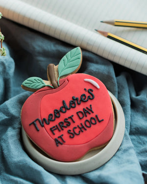 Honeywell Bakes Personalised Thank You Teacher Apple Biscuit - Cookie shaped like an apple with 'Theodore's First Day at School' text on a blue fabric background.