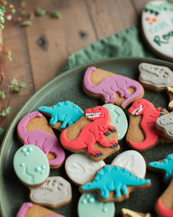 Honeywell Bakes Personalised Jar of Dinosaur Biscuits - Dinosaur-shaped cookies with colourful icing on a green plate.
