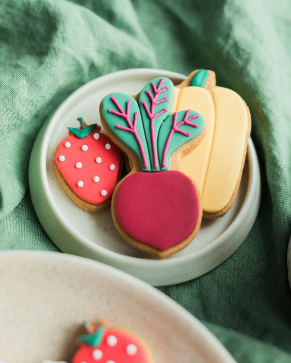 Honeywell Bakes Personalised Gardeners Fruit and Vegetable Biscuit Jar - Decorative cookies shaped like vegetables on a green fabric background