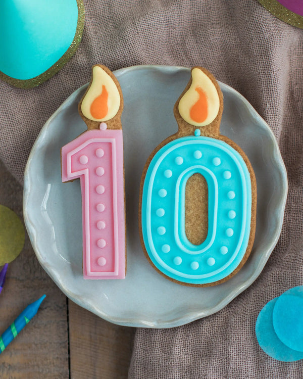 Honeywell Bakes Pick Your Own Milestone Birthday Biscuits - Two cookie cutouts shaped like birthday candles on a plate with a brown background