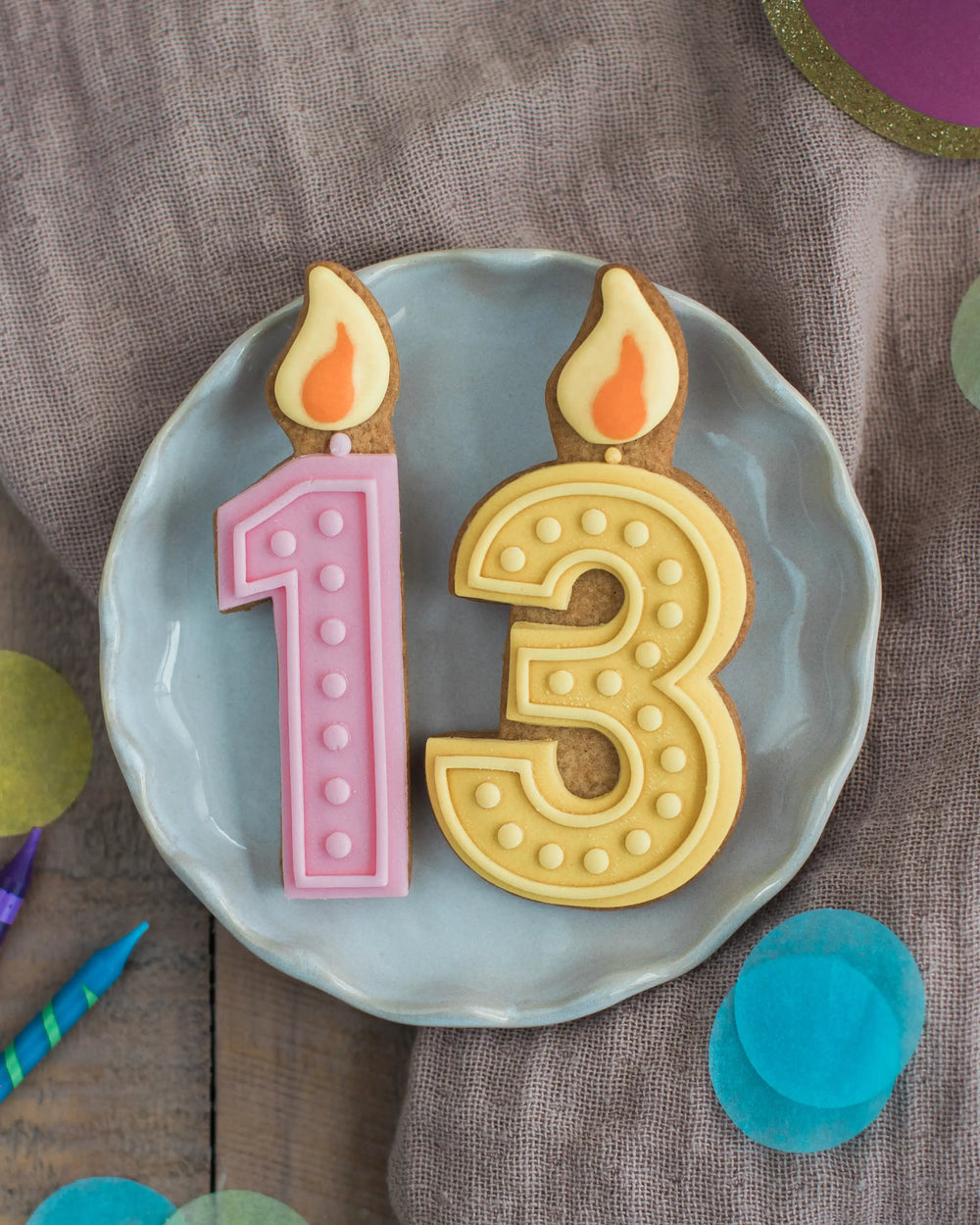 Honeywell Bakes Pick Your Own Milestone Birthday Biscuits - Colourful number cookies with candle decorations on a wooden surface.