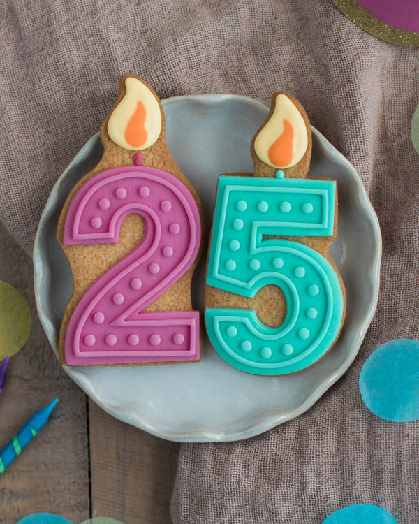 Honeywell Bakes Pick Your Own Milestone Birthday Biscuits - Two cookies shaped like candles with numbers 2 and 5 on a plate.