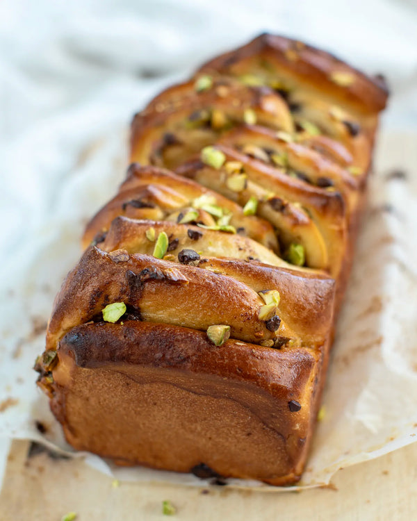 Honeywell Bakes Bread Bakers Subscription, a baked loaf of bread with a golden-brown crust, topped with chopped pistachios