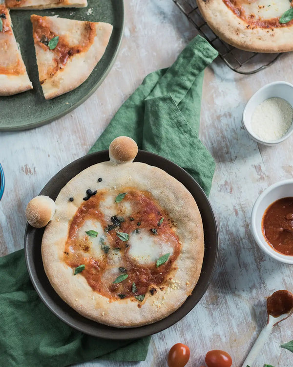 Honeywell Bakes Pizza Pet Baking Kit - 
Small pizza on a pan with ingredients around on a wooden surface