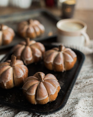 Honeywell Bakes Pumpkin Spiced Iced Bun Baking Kit - Decorative bread roll pumpkins with a glaze on a baking tray, blurred background