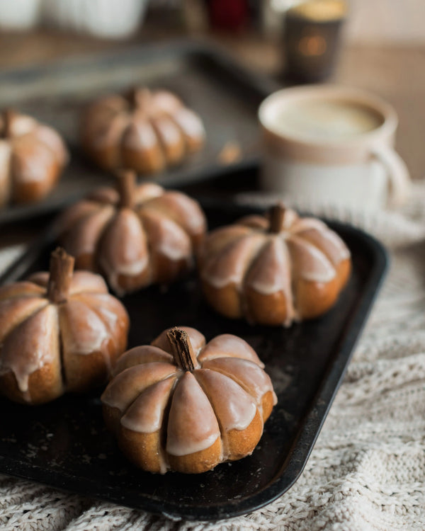 Honeywell Bakes Pumpkin Spiced Iced Bun Baking Kit - Decorative bread roll pumpkins with a glaze on a baking tray, blurred background