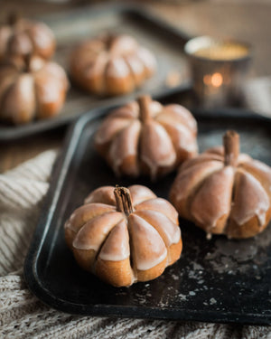 Honeywell Bakes Pumpkin Spiced Iced Bun Baking Kit - Decorative bread pumpkins on a dark tray with a soft focus background
