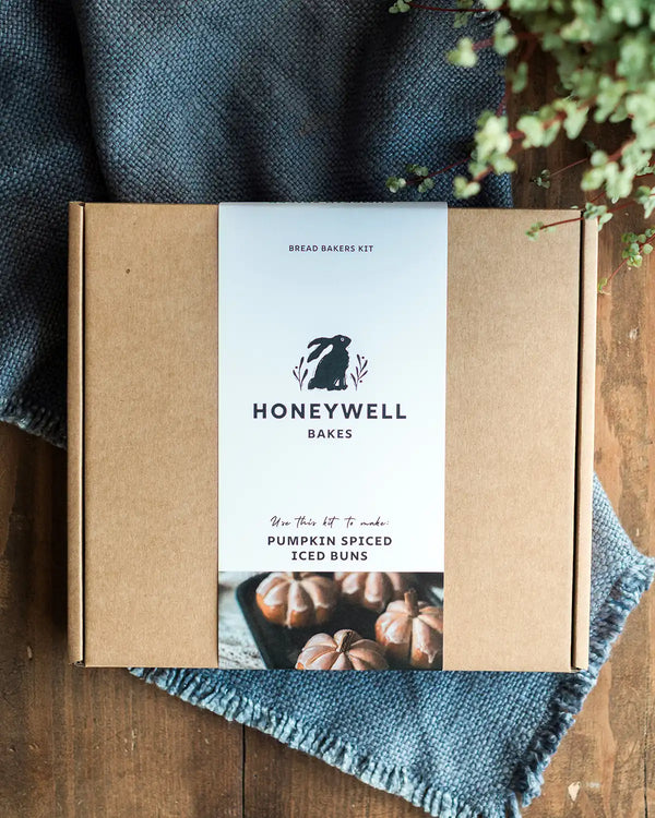 Honeywell Bakes Pumpkin Spiced Iced Bun Baking Kit on a wooden surface with a blue cloth and plant in the background