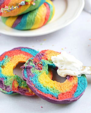 Honeywell Bakes Rainbow Bagel Bread Kit Colourful bagels sliced open on a plate with cream cheese