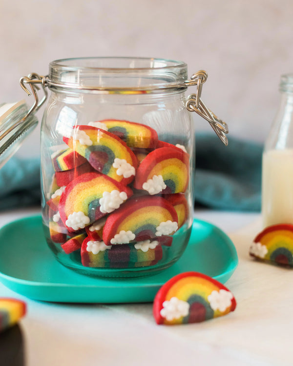 Honeywell Bakes Rainbow Biscuit Baking Kit - Glass jar filled with rainbow-shaped cookies on a teal plate with a blurred background