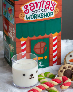 Honeywell Bakes Santa’s Cookie Workshop - 12 Days Christmas Baking Advent - A festive Santa's Cookie Workshop themed product display featuring a decorated cardboard box, a glass of milk with a bear face, and holiday cookies on a white fabric surface.