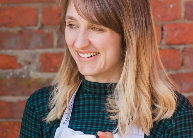 Woman holding a mug in front of a brick wall