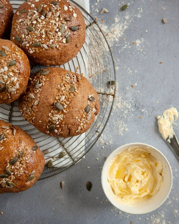 Honeywell Bakes Bread Bakers Subscription, home baked bread rolls with seeds on a cooling rack next to a bowl of butter.
