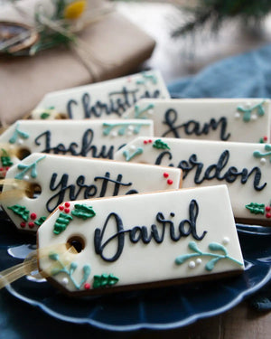Honeywell Bakes Six Personalised Christmas Tag Biscuits - Decorative name tags with Christmas-themed designs on a blue plate.