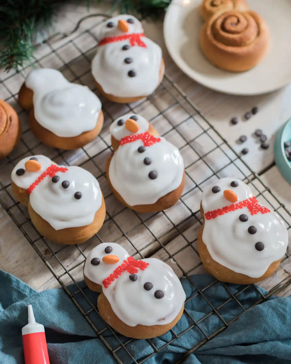 Eight homemade snowman cinnamon rolls decorated with icing