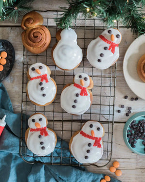 Eight homemade snowman cinnamon rolls decorated with icing