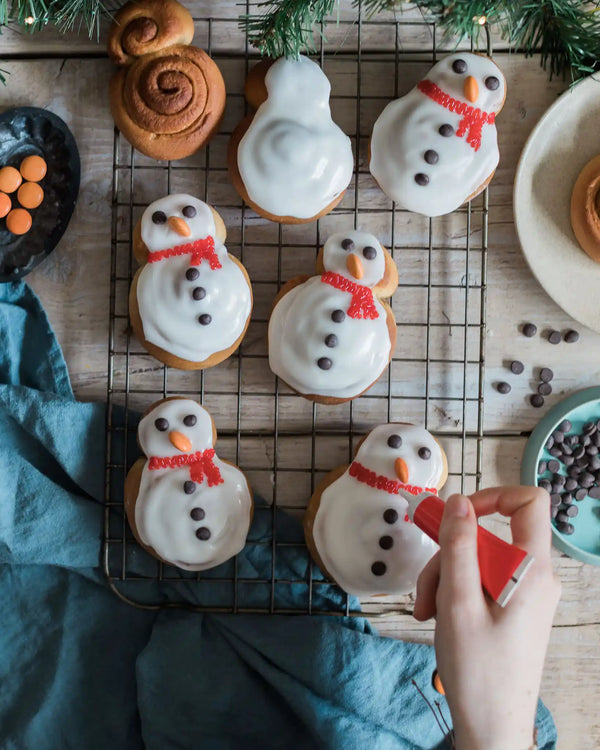 lose-up of decorated snowman cinnamon rolls with icing faces and buttons