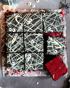 Honeywell Bakes Spooky Traybake Baking Kit - Decorative Halloween-themed brownies cut into squares on a black background with spider webs and bones.