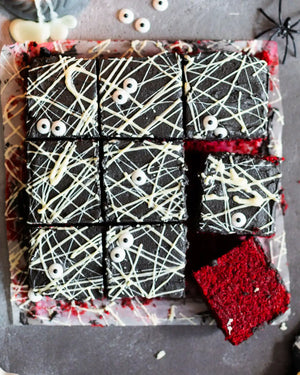 Honeywell Bakes Spooky Traybake Baking Kit - Decorative Halloween-themed brownies cut into squares on a black background with spider webs and bones.