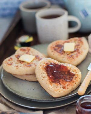 Honeywell Bakes Tea And Crumpets For Two Baking Kit - Plate of crumpets with butter and jam, accompanied by mugs in the background.
