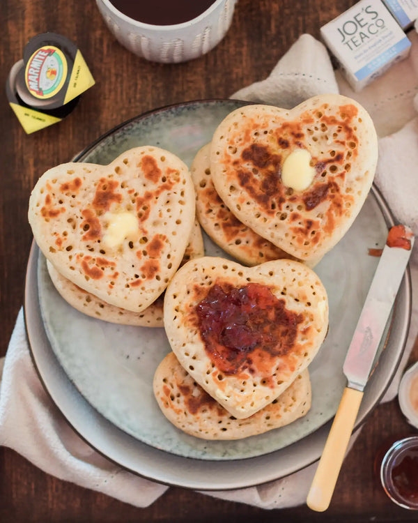 Honeywell Bakes Tea And Crumpets For Two Baking Kit - Heart-shaped crumpets on a plate with butter and jam, served with a cup of tea.