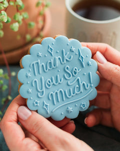 Honeywell Bakes Thank You So Much Biscuit - hands holding a light blue biscuit, embossed with a ‘Thank You So Much!’ design.