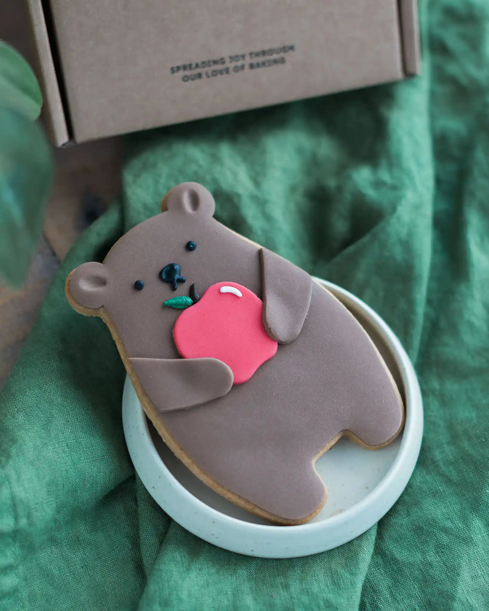 Honeywell Bakes Thank You Teacher Bear Biscuit - Cookie shaped like a bear holding an apple on a green surface
