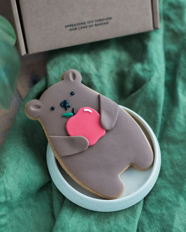 Honeywell Bakes Thank You Teacher Bear Biscuit - Cookie shaped like a bear holding an apple on a green surface