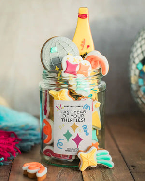 Honeywell Bakes The Celebration Jar - Jar of colourful cookies with a decorative label on a wooden surface