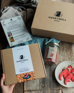 The Chilli Lovers Bundle by Honeywell Bakes, featuring a Chilli Biscuit Roulette jar of surprise-spice shortbread biscuits and a Chilli Roulette Bubble Bread baking kit with three different heat levels, presented in sustainable kraft gift packaging.