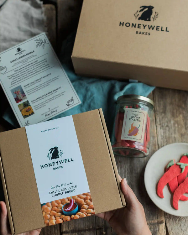 The Chilli Lovers Bundle by Honeywell Bakes, featuring a Chilli Biscuit Roulette jar of surprise-spice shortbread biscuits and a Chilli Roulette Bubble Bread baking kit with three different heat levels, presented in sustainable kraft gift packaging.