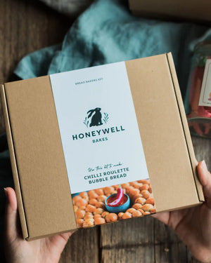 The Chilli Lovers Bundle by Honeywell Bakes, featuring a Chilli Biscuit Roulette jar of surprise-spice shortbread biscuits and a Chilli Roulette Bubble Bread baking kit with three different heat levels, presented in sustainable kraft gift packaging.