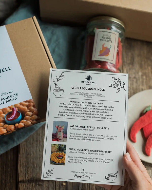The Chilli Lovers Bundle by Honeywell Bakes, featuring a Chilli Biscuit Roulette jar of surprise-spice shortbread biscuits and a Chilli Roulette Bubble Bread baking kit with three different heat levels, presented in sustainable kraft gift packaging.
