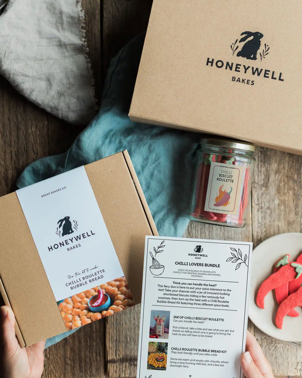 The Chilli Lovers Bundle by Honeywell Bakes, featuring a Chilli Biscuit Roulette jar of surprise-spice shortbread biscuits and a Chilli Roulette Bubble Bread baking kit with three different heat levels, presented in sustainable kraft gift packaging.