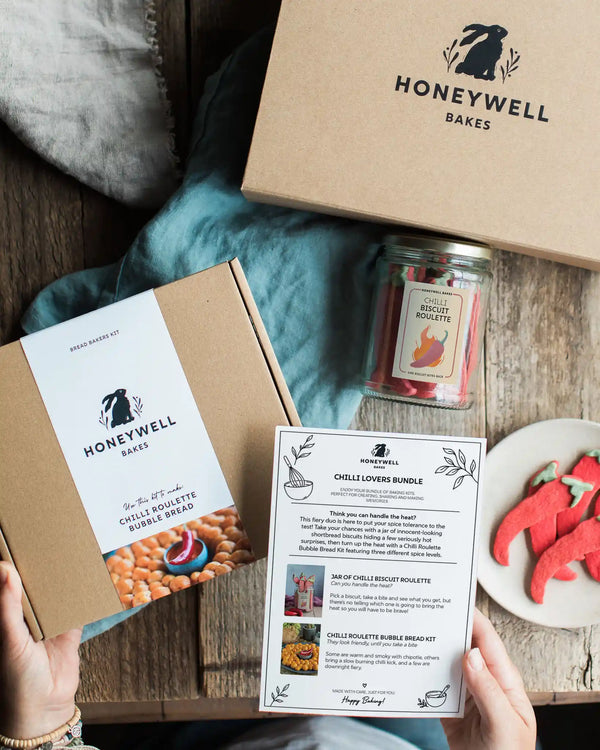The Chilli Lovers Bundle by Honeywell Bakes, featuring a Chilli Biscuit Roulette jar of surprise-spice shortbread biscuits and a Chilli Roulette Bubble Bread baking kit with three different heat levels, presented in sustainable kraft gift packaging.