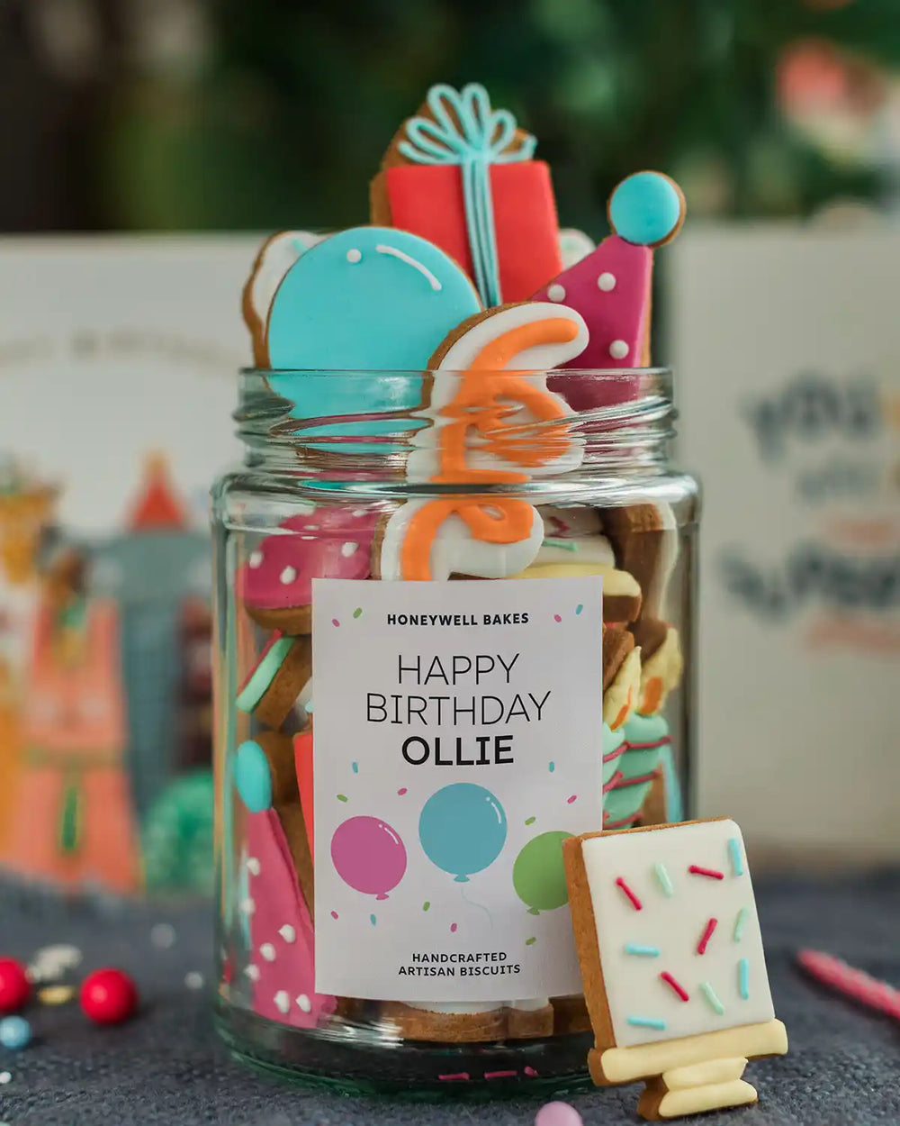 Honeywell Bakes The Happy Birthday Biscuit Jar - Jar of colourful cookies with a personalised birthday card on a festive background