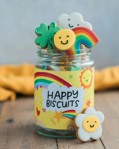 Honeywell Bakes The Happy News Biscuit Jar - Jar of colourful cookies with a 'Happy Biscuits' label on a wooden surface