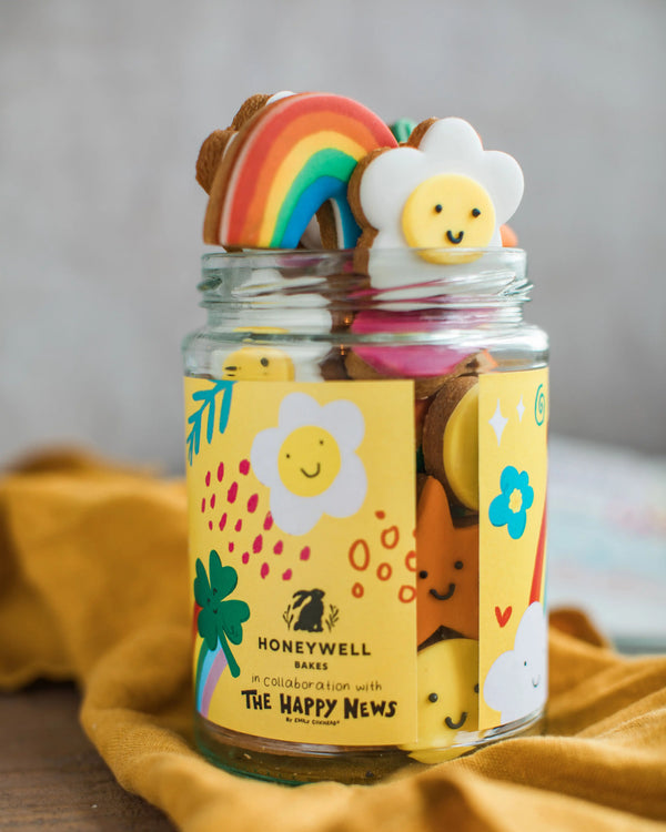 Honeywell Bakes The Happy News Biscuit Jar - Jar with colourful cookies on a yellow cloth
