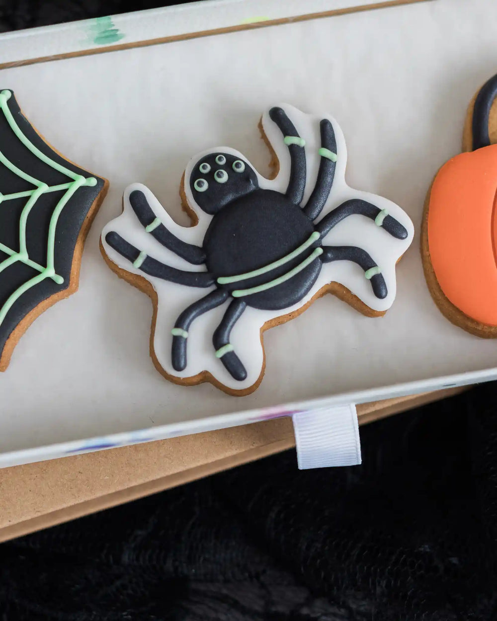 Honeywell Bakes Trick Or Treat Biscuit Gift - Box of Halloween-themed cookies with decorative elements on a dark background.