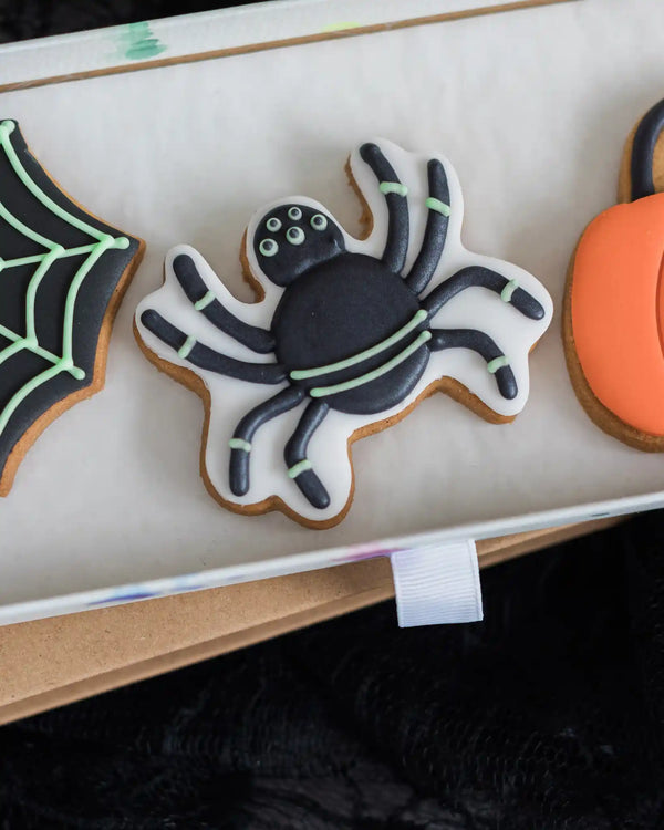 Honeywell Bakes Trick Or Treat Biscuit Gift - Halloween-themed cookies including a spider, web, and pumpkin on a white surface.