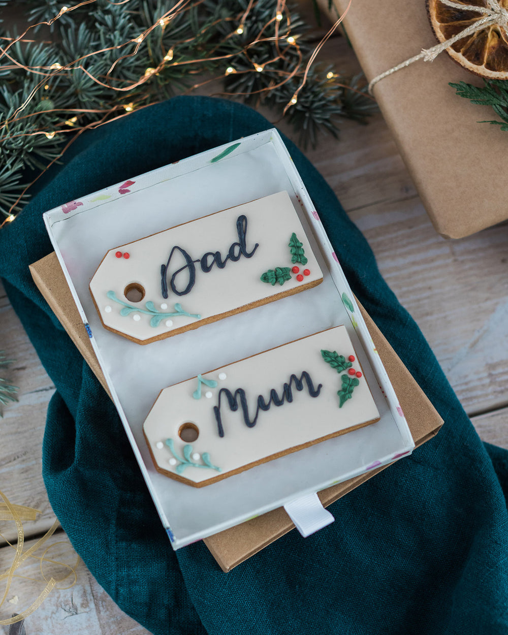 Honeywell Bakes Two Personalised Christmas Tag Biscuits - two Christmas themed decorated biscuits, held in a box with a blurred background